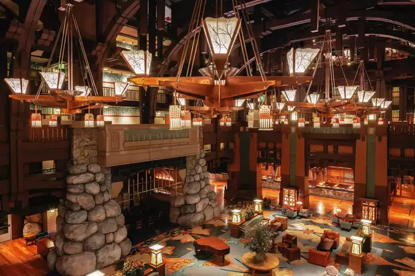 View of the Grand Californian Hotel lobby at Disneyland, featuring rock pillars, wooden chandeliers, and seating areas.