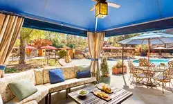 Poolside cabana with seating and a view of the pool and surrounding area, featuring a dining table and refreshments on a central table