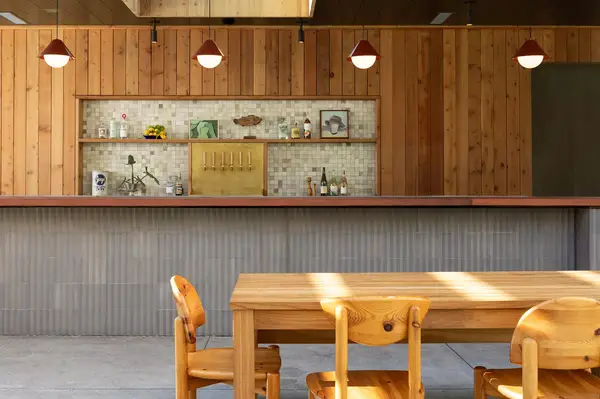 Outdoor bar setup, wooden paneling, with a visible table and chairs in the foreground
