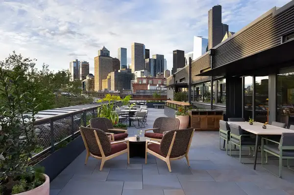 A rooftop patio with seating and a view of a city