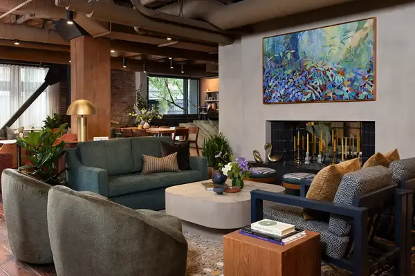 Interior of a lounge with cozy seating, a fireplace with candles, and wall art above it