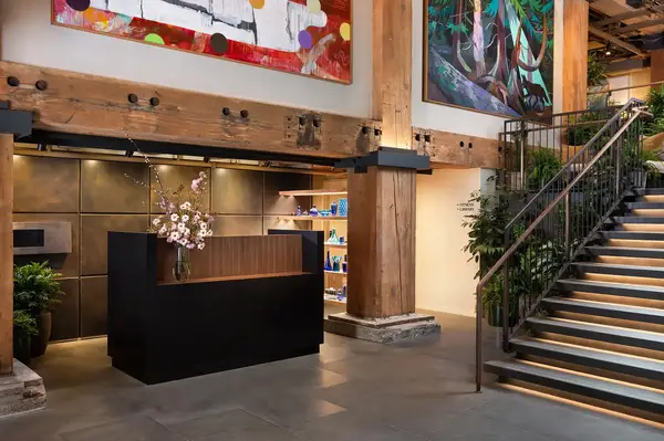 Front desk area with artwork, staircase, and wooden beams