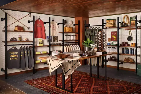A rustic shop interior featuring various Field & Stream apparel and accessories displayed on shelves and tables