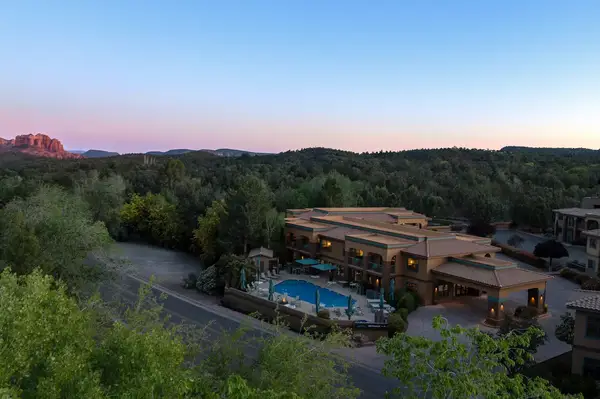 A modern building with a swimming pool surrounded by trees in a mountainous landscape