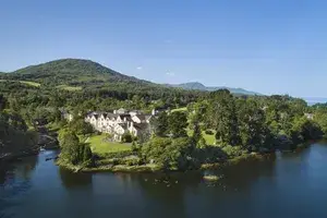 A scenic view of Sheen Falls Lodge surrounded by trees water and hills