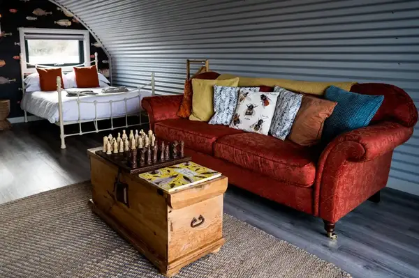 A cozy room with a sofa bed and a wooden chest with a chess set