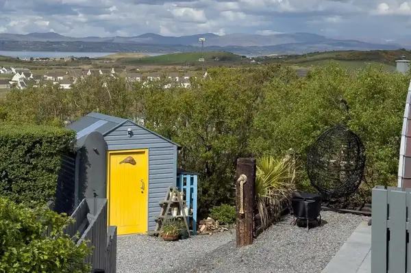 Outdoor area with a small shed garden decor and surrounding greenery with hills visible in the background