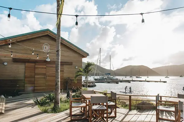Outdoor seating area near a wooden building and marina with moored boats