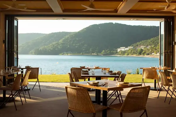 Outdoor dining area overlooking a serene water view and surrounding hills