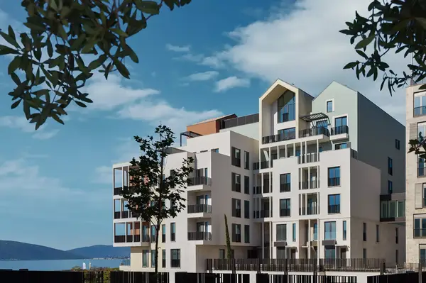 Modern residential building complex with contemporary architecture near a body of water, trees framing the view