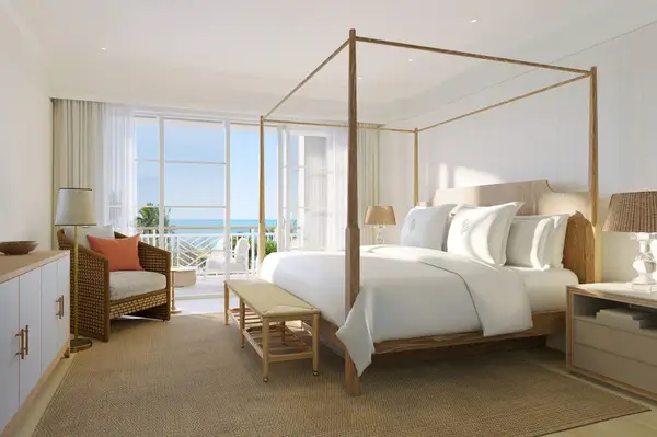 Suite bedroom featuring a four-poster bed and a view of the ocean through large glass doors