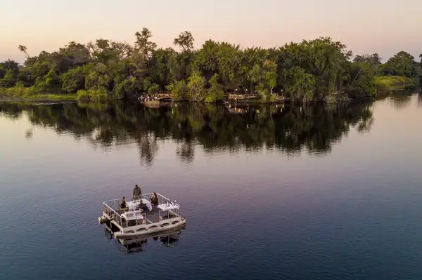 Floating deck on a calm lake near a forested lodge in Botswana