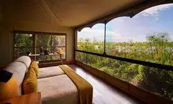 A guestroom with dual beds and an open view of the surrounding greenery and wetland at Xugana Island Lodge, Botswana