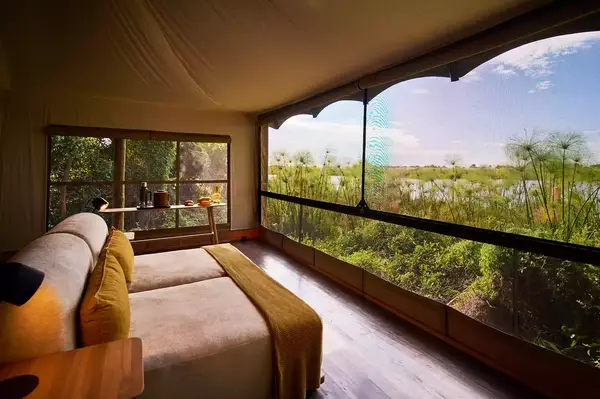 A guestroom with dual beds and an open view of the surrounding greenery and wetland at Xugana Island Lodge, Botswana