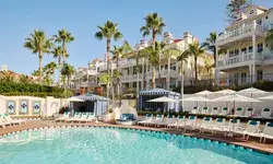 Outdoor pool area of a luxury beachside resort with palm trees and multi-story buildings