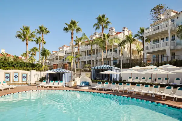 Outdoor pool area of a luxury beachside resort with palm trees and multi-story buildings