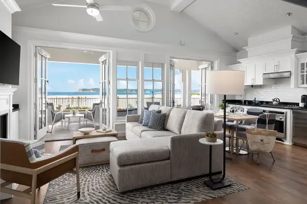 Beachfront cottage living room with ocean view, open layout with seating area, kitchen, and French doors leading to a patio