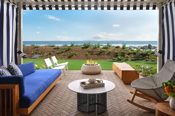 A terrace with a lounging setup, fire pit, and ocean view