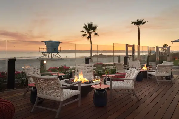 Firepit seating area on a wooden deck overlooking the beach at sunset