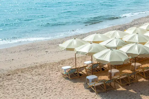 Rows of beach chairs and umbrellas line the beach while the waves come in 
