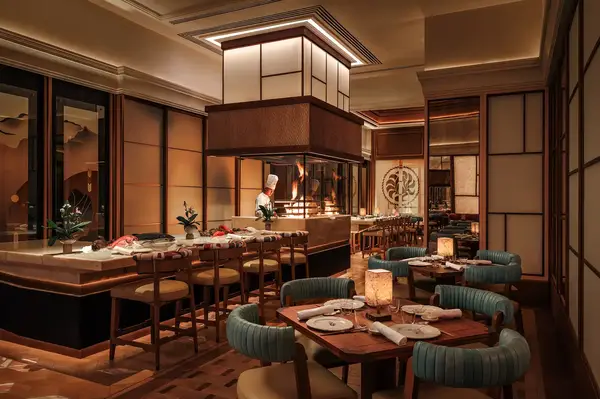 Modern restaurant interior with dining tables chairs a counter with a chef and decorative lighting