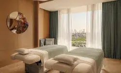 Spa room with two treatment tables and a large window overlooking a city view