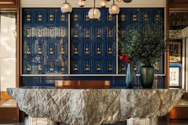 Luxurious lobby area featuring a textured stone counter decorative pottery vases and a wall with colorful patterned panels and lighting