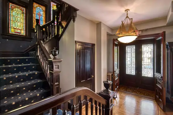 Interior of a home with a staircase, stained glass windows, and a chandelier in the entryway