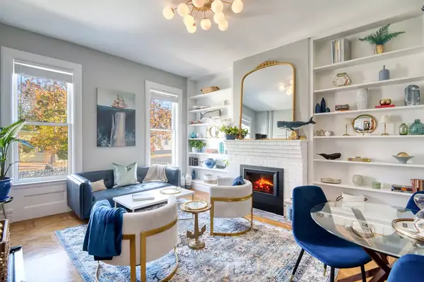 Bright, stylish living room with modern furnishings, a fireplace, a large mirror, and built-in bookshelves