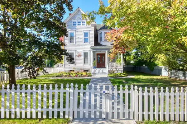 A house with a pathway, a white picket fence, and trees