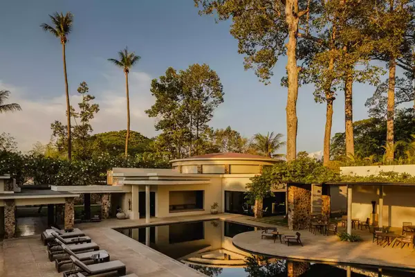 Exterior view of the main resort pool and towering palm trees during golden hour at Amansara