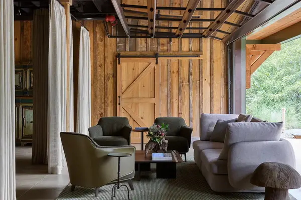 A rusticstyle interior with armchairs a sofa a wooden sliding door and an outdoor view