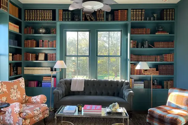 A cozy library with a window shelves full of books and furniture arranged for reading and relaxing