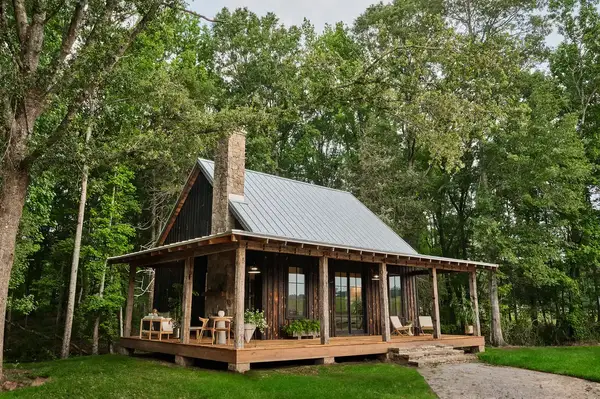 Rustic cabin with a porch surrounded by trees and greenery
