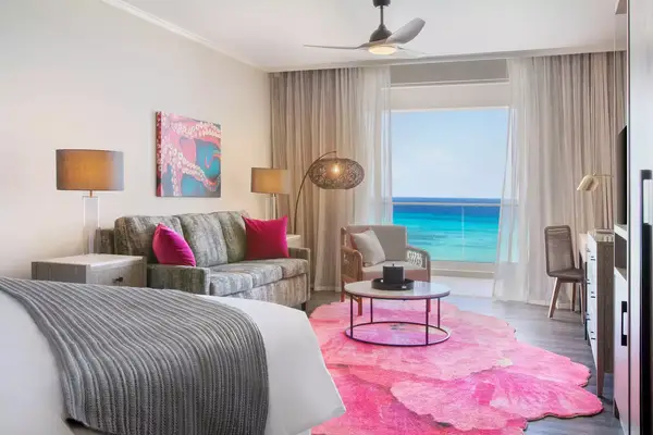 Hotel room with a sofa and a bed, ocean view through glass doors