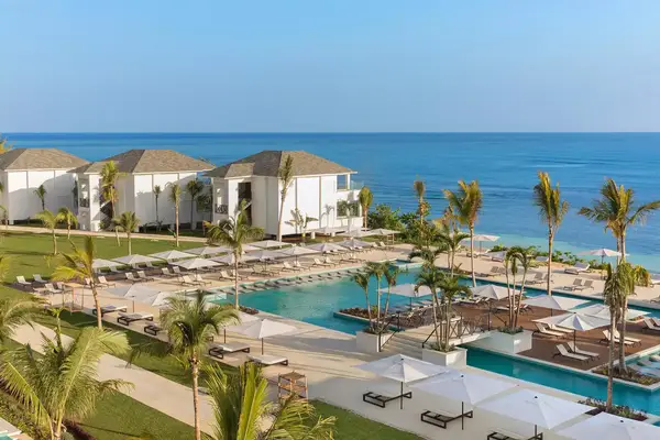 Luxurious beachfront resort complex with pools and lounge areas, overlooking the ocean