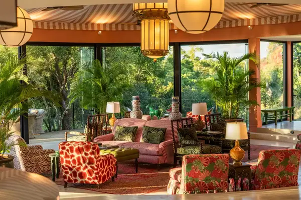 A tastefully furnished living room with large windows, tropical-themed decor, and vibrant seating arrangements in a luxurious setting