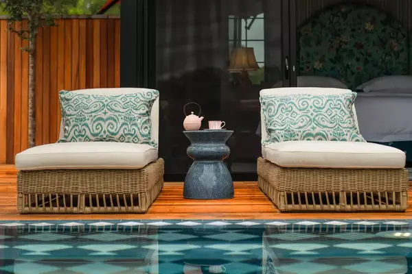 Poolside lounge chairs and a small table with teapot and cup