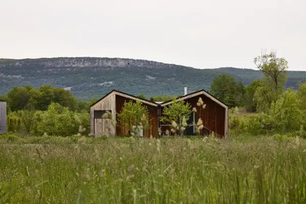 Scenic cabin surrounded by wild grasses with a hilly landscape in the background