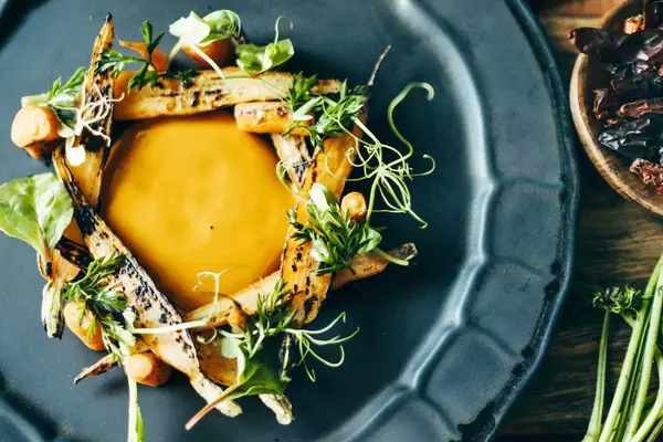 Grilled carrots and carrot puree on a grey plate at Palmaia resort, in Mexico
