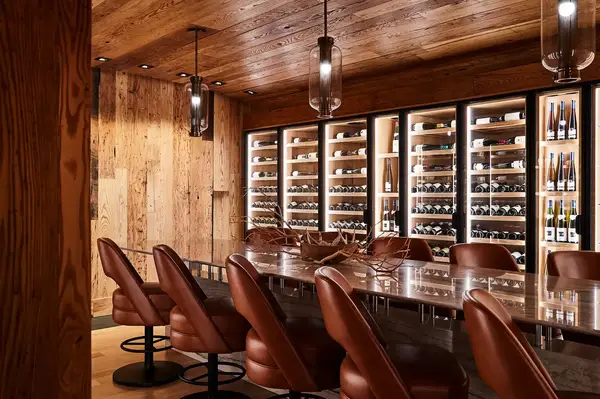 A wine cellar interior with a bar and chairs featuring shelves filled with wine bottles