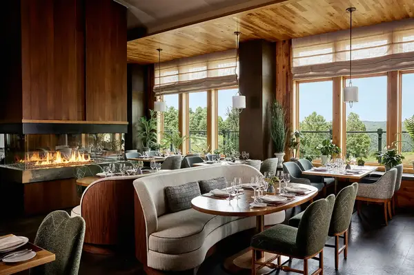 A cozy dining area featuring a fireplace and large windows with a scenic view at Primland Resort in Virginia