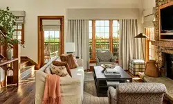 A cozy living room with a stone fireplace sofas and large windows opening to a terrace