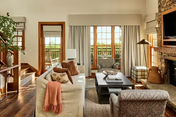 A cozy living room with a stone fireplace sofas and large windows opening to a terrace
