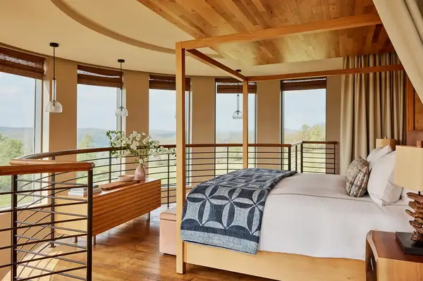 A bedroom with a fourposter bed large windows overlooking a scenic view and modern decor