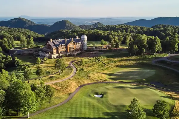 A large resort surrounded by golf greens and wooded hills