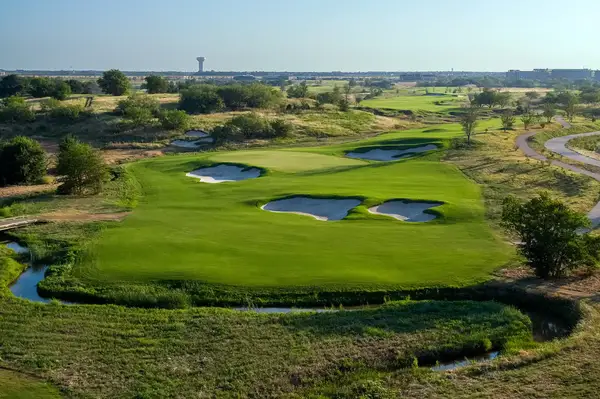 A golf course view with bunkers, greenery, and a winding path