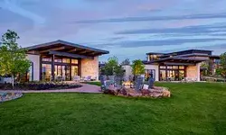 Lodge-style ranch house exterior with surrounding landscaped garden and patio chairs