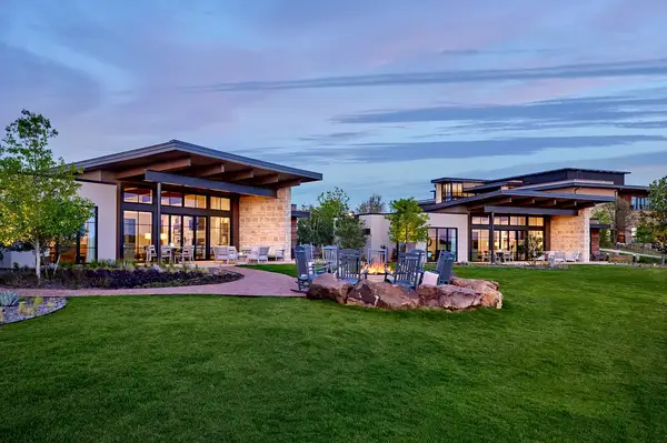 Lodge-style ranch house exterior with surrounding landscaped garden and patio chairs