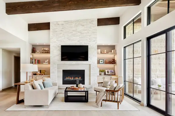 Modern living room with a fireplace, a sofa, chairs, and decorative shelving